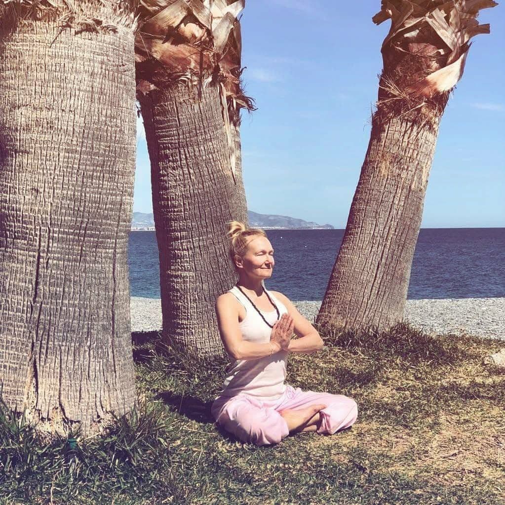 Ewa i meditation under palmerna vid havet